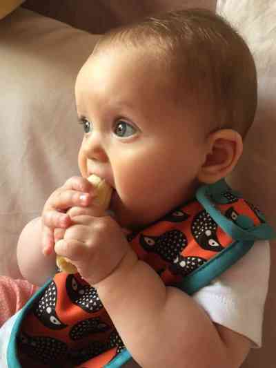 Niña de 7 meses comiendo un plátano con sus manos